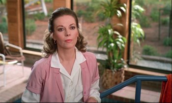 Movie still from “Brainstorm” (1983), directed by Douglas Trumbull – A woman in a pink jacket sitting on a chair; Close Up shot, Over the shoulder angle