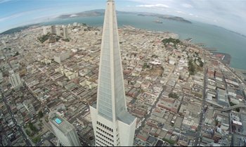 Movie still from “Brainstorm” (1983), directed by Douglas Trumbull – An aerial view of a city with buildings and a large skyscraper in the foreground; Extreme Wide shot, Overhead angle