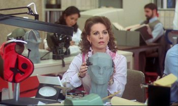 Movie still from “Brainstorm” (1983), directed by Douglas Trumbull – A woman sitting at a desk with a head sculpture in front of her; Close Up shot, Over the shoulder angle