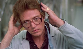 Movie still from “Brainstorm” (1983), directed by Douglas Trumbull – A man with glasses is putting on his hair; Close Up shot, Low angle