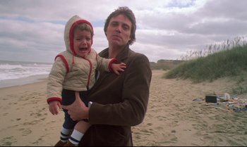 Movie still from “Brainstorm” (1983), directed by Douglas Trumbull – A man holding a child on the beach; Medium shot, Low angle
