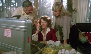 Movie still from “Brainstorm” (1983), directed by Douglas Trumbull – A woman on the phone with two men looking on; Medium shot, High angle