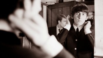 Movie still from “The Beatles: Eight Days a Week - The Touring Years” (2016), directed by Ron Howard – A man in a suit and tie in front of another man in a suit and tie in front of a mirror; Close Up shot, Over the shoulder angle
