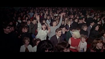 Movie still from “The Beatles: Eight Days a Week - The Touring Years” (2016), directed by Ron Howard – A large crowd of people are gathered in a room; Wide shot, High angle