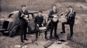 Movie still from “The Beatles: Eight Days a Week - The Touring Years” (2016), directed by Ron Howard – A black and white photo of a group of men playing instruments; Extreme Wide shot, High angle