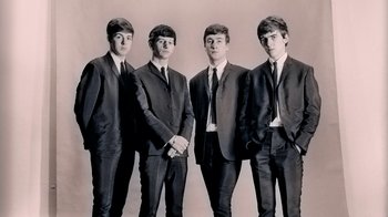 Movie still from “The Beatles: Eight Days a Week - The Touring Years” (2016), directed by Ron Howard – A group of men standing next to each other in suits; Medium shot, Low angle