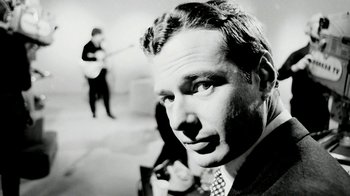 Movie still from “The Beatles: Eight Days a Week - The Touring Years” (2016), directed by Ron Howard – A black and white photo of a man in a suit and tie; Close Up shot, Low angle