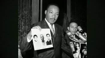 Movie still from “The Beatles: Eight Days a Week - The Touring Years” (2016), directed by Ron Howard – A black and white photo of a man holding up a picture; Close Up shot, Low angle