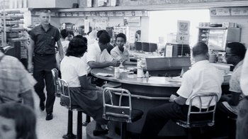 Movie still from “The Beatles: Eight Days a Week - The Touring Years” (2016), directed by Ron Howard – A group of people sitting at a table in a restaurant; Wide shot, High angle