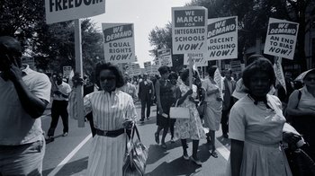 Movie still from “The Beatles: Eight Days a Week - The Touring Years” (2016), directed by Ron Howard – A black and white photo of people holding protest signs; Extreme Wide shot, High angle