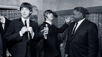 Movie still from “The Beatles: Eight Days a Week - The Touring Years” (2016), directed by Ron Howard – A black and white photo of a group of men in suits and ties; Medium shot, High angle