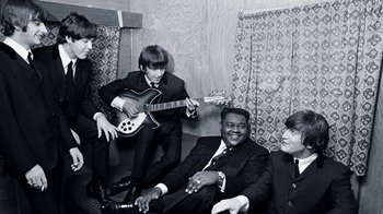 Movie still from “The Beatles: Eight Days a Week - The Touring Years” (2016), directed by Ron Howard – A black and white photo of a group of men in suits and ties; Medium shot, High angle