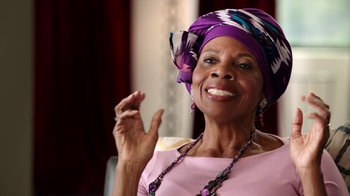 Movie still from “The Beatles: Eight Days a Week - The Touring Years” (2016), directed by Ron Howard – An older woman wearing a purple head scarf; Close Up shot, Low angle