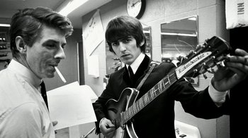 Movie still from “The Beatles: Eight Days a Week - The Touring Years” (2016), directed by Ron Howard – A man in a suit and tie holding a guitar; Close Up shot, Low angle