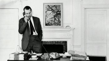 Movie still from “The Beatles: Eight Days a Week - The Touring Years” (2016), directed by Ron Howard – A black and white photo of a man talking on a phone; Medium shot, Low angle