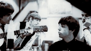 Movie still from “The Beatles: Eight Days a Week - The Touring Years” (2016), directed by Ron Howard – Two young men are playing guitar in a room; Close Up shot, Over the shoulder angle