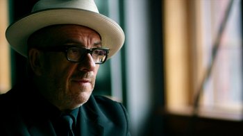 Movie still from “The Beatles: Eight Days a Week - The Touring Years” (2016), directed by Ron Howard – A person wearing glasses and a hat; Close Up shot, Low angle