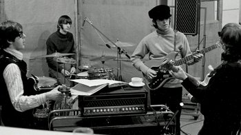 Movie still from “The Beatles: Eight Days a Week - The Touring Years” (2016), directed by Ron Howard – A black and white photo of a group of men playing instruments; Medium shot, Low angle