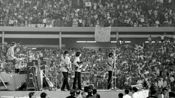 Movie still from “The Beatles: Eight Days a Week - The Touring Years” (2016), directed by Ron Howard – A group of people that are standing in front of a crowd; Extreme Wide shot, High angle