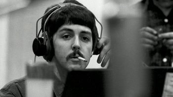 Movie still from “The Beatles: Eight Days a Week - The Touring Years” (2016), directed by Ron Howard – A man wearing headphones and smoking a cigarette while looking at a computer screen; Close Up shot, Low angle