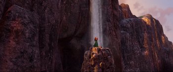 Movie still from “Brave” (2012), directed by Steve Purcell – A person standing on top of a rock near a waterfall; Extreme Wide shot, Low angle