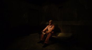 A man sitting on top of a bench in a dark room