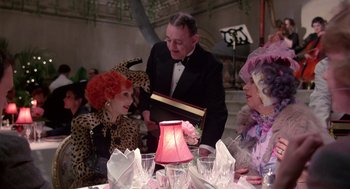 Movie still from “Brazil” (1985), directed by Terry Gilliam – A group of people sitting at a table with a book; Medium shot, Over the shoulder angle