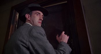 Movie still from “Brazil” (1985), directed by Terry Gilliam – A man wearing a hat and a suit; Close Up shot, Low angle