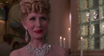 Movie still from “Brazil” (1985), directed by Terry Gilliam – An older woman wearing a diamond necklace and earrings; Close Up shot, Over the shoulder angle
