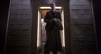 Movie still from “Brazil” (1985), directed by Terry Gilliam – A man standing in front of a door way; Wide shot, Low angle