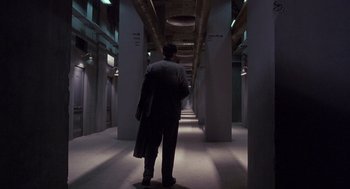 Movie still from “Brazil” (1985), directed by Terry Gilliam – A man standing in a dark hallway with pillars; Extreme Wide shot, High angle