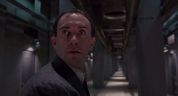 Movie still from “Brazil” (1985), directed by Terry Gilliam – A man in a suit standing in a dark hallway; Close Up shot, Low angle