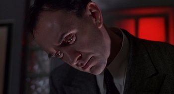 Movie still from “Brazil” (1985), directed by Terry Gilliam – A person wearing a suit and tie; Close Up shot, Low angle