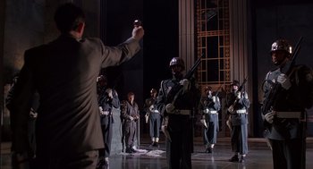 Movie still from “Brazil” (1985), directed by Terry Gilliam – A group of men in military uniforms standing in front of a building; Wide shot, Low angle