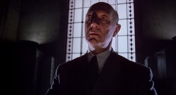 Movie still from “Brazil” (1985), directed by Terry Gilliam – A man in a suit and tie looking to his left; Close Up shot, Low angle