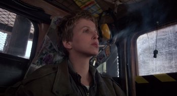 Movie still from “Brazil” (1985), directed by Terry Gilliam – A young man is smoking a cigarette while sitting on a train; Close Up shot, Low angle