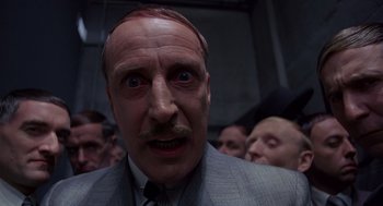 Movie still from “Brazil” (1985), directed by Terry Gilliam – A person wearing a suit and tie; Close Up shot, Low angle