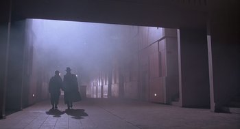 Movie still from “Brazil” (1985), directed by Terry Gilliam – Two people are walking in the fog on a sidewalk; Wide shot, Low angle