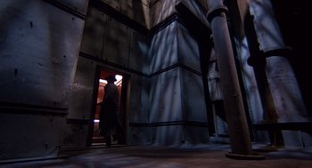 Movie still from “Brazil” (1985), directed by Terry Gilliam – A man standing in a doorway of an industrial building; Extreme Wide shot, Low angle