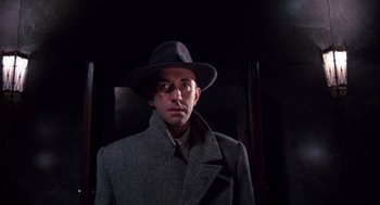 Movie still from “Brazil” (1985), directed by Terry Gilliam – A man wearing a hat and a coat; Close Up shot, Low angle