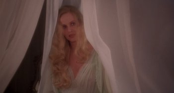 Movie still from “Brazil” (1985), directed by Terry Gilliam – A woman with long blonde hair standing in front of a curtain; Close Up shot, Over the shoulder angle