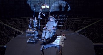 Movie still from “Brazil” (1985), directed by Terry Gilliam – A scene of a man lying on a bed next to another man; Wide shot, High angle