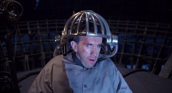 Movie still from “Brazil” (1985), directed by Terry Gilliam – A man wearing a metal helmet and a gray jacket; Close Up shot, High angle