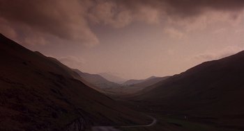 Movie still from “Brazil” (1985), directed by Terry Gilliam – A view of a mountain range with a cloudy sky above it; Extreme Wide shot, Low angle