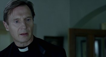 Movie still from “Breakfast on Pluto” (2005), directed by Neil Jordan – A man wearing a priest's outfit looking at the camera; Close Up shot, Low angle