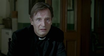 Movie still from “Breakfast on Pluto” (2005), directed by Neil Jordan – A man wearing a priest's collar and a black robe; Close Up shot, Low angle