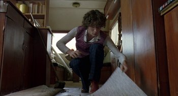 Movie still from “Breakfast on Pluto” (2005), directed by Neil Jordan – A woman is kneeling on the floor in a room; Medium shot, Low angle