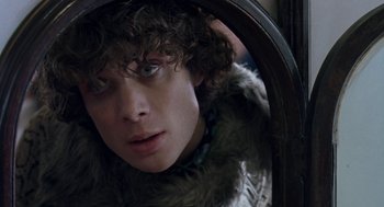 Movie still from “Breakfast on Pluto” (2005), directed by Neil Jordan – A young man looking into a mirror in a fur coat; Close Up shot, Over the shoulder angle