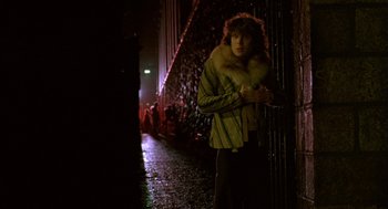 Movie still from “Breakfast on Pluto” (2005), directed by Neil Jordan – A person standing in the dark wearing a coat; Medium shot, Low angle