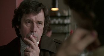 Movie still from “Breakfast on Pluto” (2005), directed by Neil Jordan – A person sitting at a table with his hand under his chin; Close Up shot, Over the shoulder angle